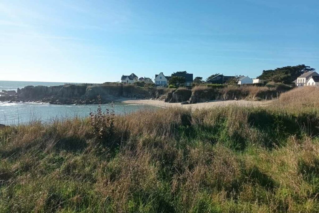 Balades & Randonnées avec son chien : plage dans une crique de la côte sauvage surplombée par des maisons au Pouliguen